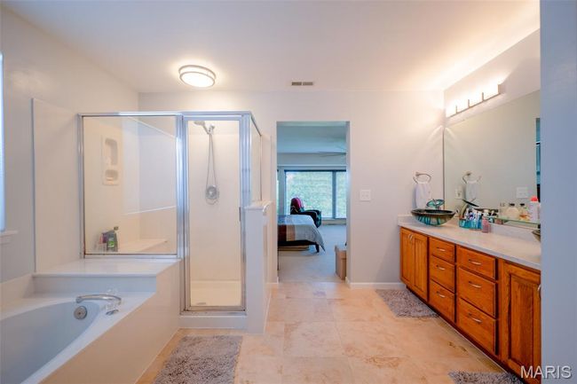 Ensuite bathroom featuring double vanity, a shower stall, and a bath | Image 30