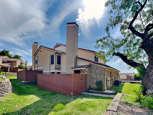 Back of property with a tiled roof, central air condition unit, a chimney, fence, and a yard | Image 21