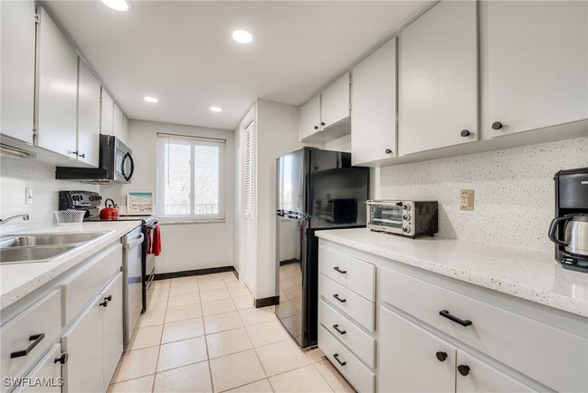Kitchen featuring sink, light tile patterned floors, appliances with stainless steel finishes, white cabinetry, and tasteful backsplash | Image 24
