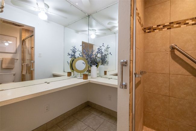 Bathroom featuring a stall shower, tile patterned flooring, vanity, ceiling fan, and toilet | Image 12