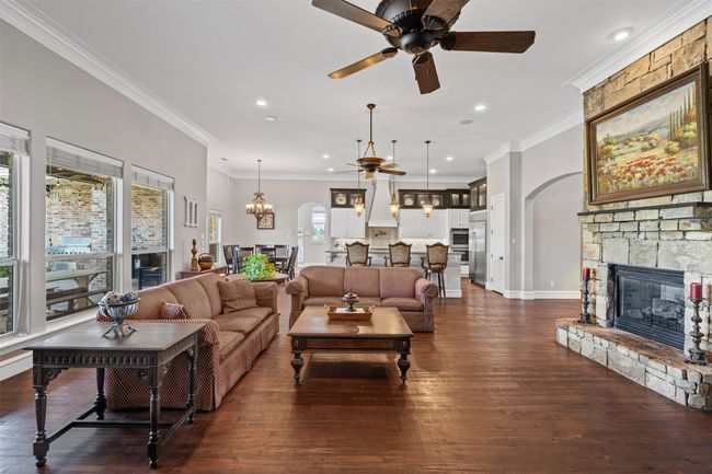 Living area featuring arched walkways, a fireplace, recessed lighting, ceiling fan with notable chandelier, and dark wood-type flooring | Image 12