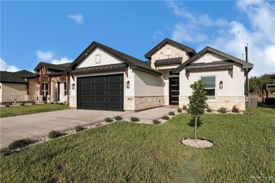 View of front of house featuring a garage, a front lawn, and central AC | Image 2