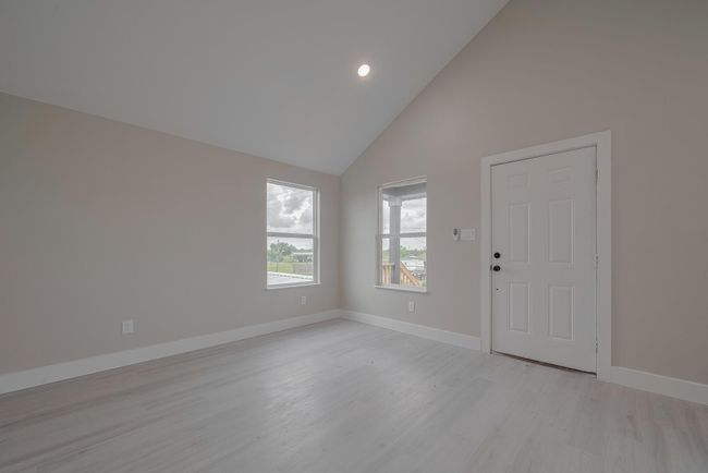 Bright and open, the living area impresses with a vaulted ceiling, recessed lighting, and large windows that draw in sunlight. Flows seamlessly into the kitchen. | Image 7