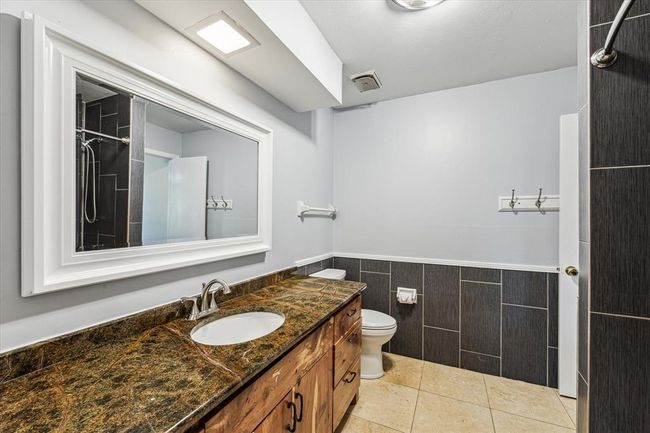 Third full bathroom is updated featuring a cedar cabinetry, new mirrors, accent tile surround and granite counter tops | Image 30