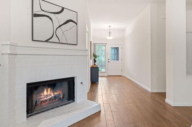 A corner fireplace framed in a brick hearth sets a warm atmosphere for cozy winter evenings. | Image 10