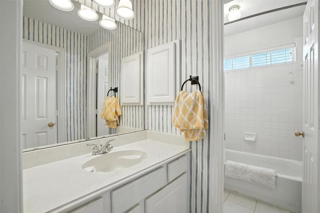 Full bath with wallpapered walls, vanity, tile patterned flooring, and shower / bath combination with curtain | Image 25