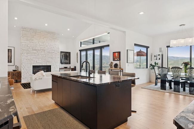 Kitchen featuring modern cabinets, plenty of natural light, light wood finished floors, a stone fireplace, and high vaulted ceiling | Image 18