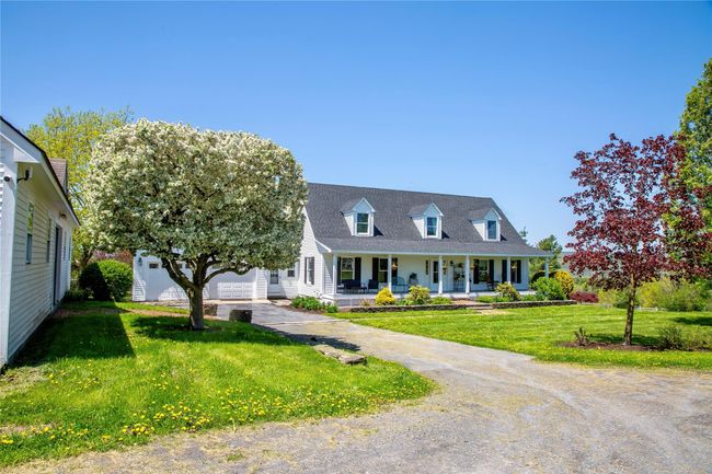 Cape cod home with covered porch, driveway, a front yard, and a garage | Image 43