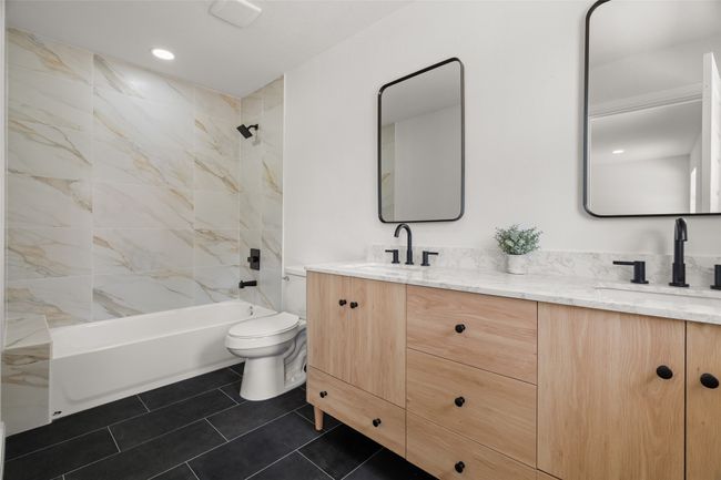 Bathroom with toilet, double vanity, tub / shower combination, and tile patterned flooring | Image 15