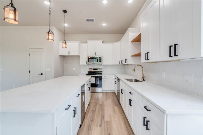 Kitchen with stainless steel appliances, open shelves, a center island, light wood-style flooring, and decorative backsplash | Image 10