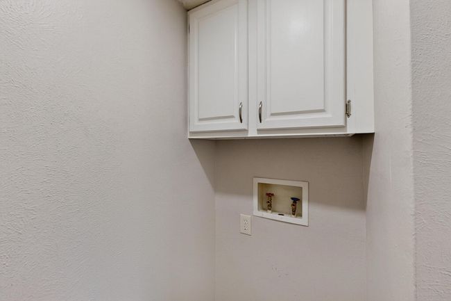 Laundry room with hookup for a washing machine, cabinet space, and a textured wall | Image 19