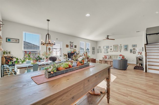 Dining room featuring ceiling fan with notable chandelier, stairway, light wood-style floors, and a healthy amount of sunlight | Image 11