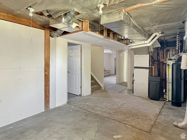 Unfinished below grade area featuring stairway and a water softener system | Image 27