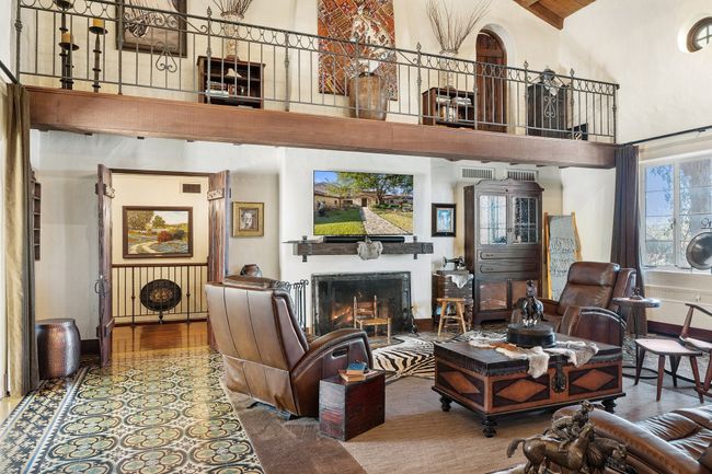 Living area with baseboards, wood finished floors, a towering ceiling, and a lit fireplace | Image 14