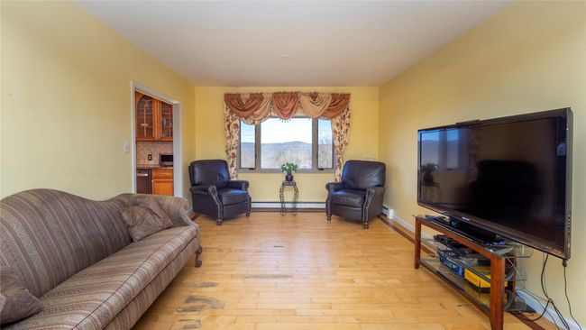 Living area with light wood-style flooring, a baseboard heating unit, and baseboards | Image 16