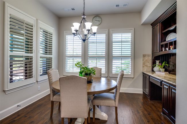 The breakfast room is the perfect spot for morning coffee, offering views of the spacious backyard and serene water. Surrounded by windows, natural light fills the space. A built-in desk adds both storage and functionality, making it an ideal spot for homework or organizing daily tasks. | Image 14