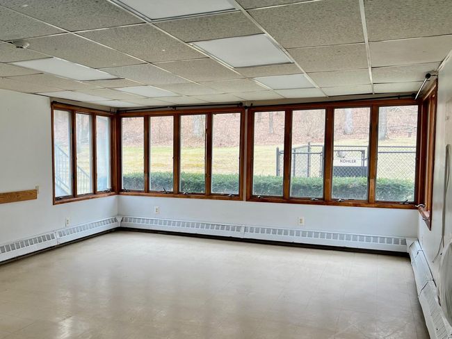 Empty room with tile patterned floors, baseboard heating, and a paneled ceiling | Image 13
