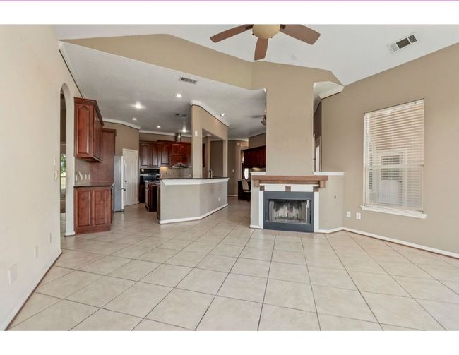 Unfurnished living room featuring light tile patterned flooring, ceiling fan, a fireplace, recessed lighting, and arched walkways | Image 20