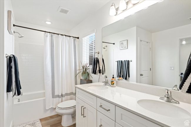 Bathroom featuring wood finished floors, double vanity, and shower / bath combo | Image 22