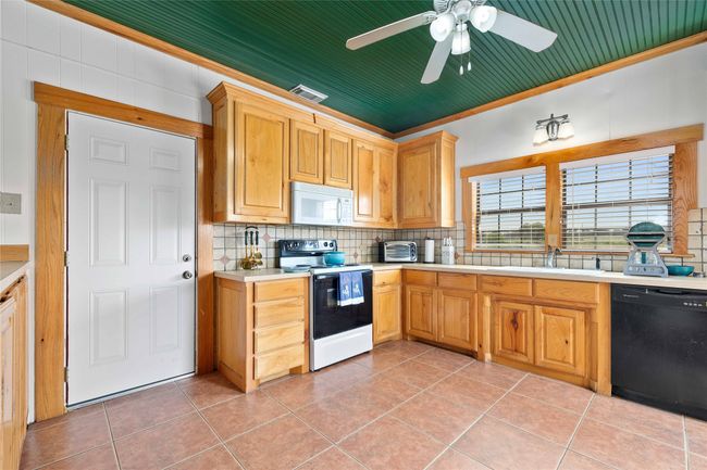 Kitchen featuring range with electric cooktop, dishwasher, white microwave, tasteful backsplash, and ornamental molding | Image 15