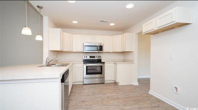 Kitchen featuring light wood-type flooring, light countertops, recessed lighting, stainless steel appliances, and a sink | Image 10