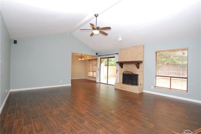 Unfurnished living room with a ceiling fan, a fireplace, and dark wood-style flooring | Image 5