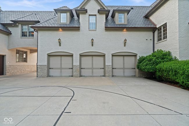 view of front facade with a high end roof, a garage, concrete driveway, and brick siding | Image 110