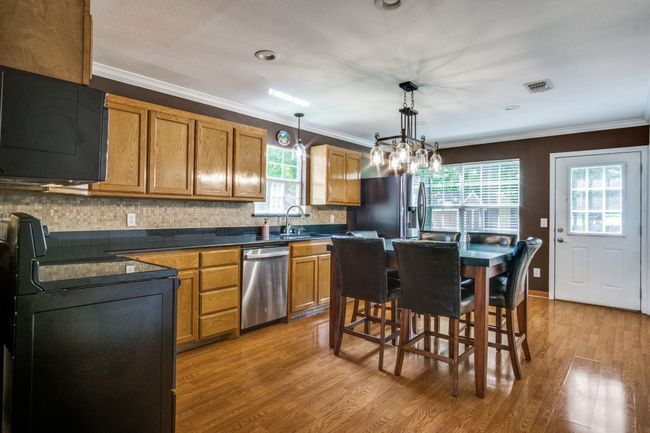 Kitchen featuring dishwasher, range, dark countertops, light wood-style floors, and crown molding | Image 11