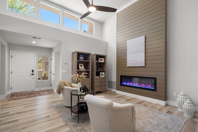 Inside you'll discover soaring majestic ceilings, an open-concept floor plan, sleek pocket windows, & warm natural light. The upgraded interior features luxury flooring, fresh designer paint, & new baseboards. Relax by the linear fireplace or entertain in the formal dining area. | Image 10