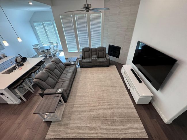 Living area with dark wood-type flooring, ceiling fan, and a large fireplace | Image 4