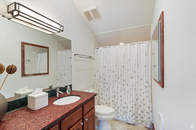 Bathroom with toilet, visible vents, lofted ceiling, tile patterned flooring, and vanity | Image 15