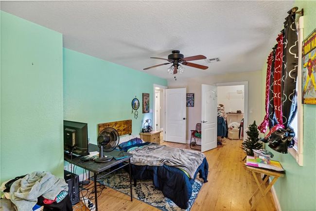 Bedroom with ceiling fan, a textured ceiling, and light wood-type flooring | Image 38