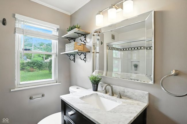 full bathroom featuring a tile shower, vanity, and ornamental molding | Image 27