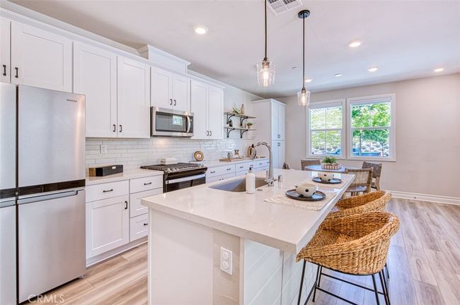 Gourmet kitchen with quartz countertops, breakfast bar island, white custom cabinetry and dining area. | Image 5