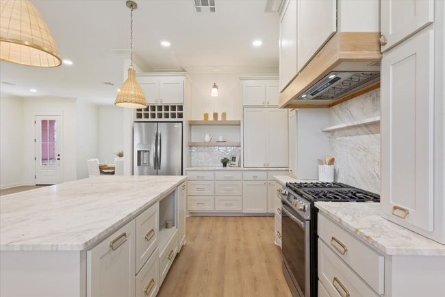 Kitchen with appliances with stainless steel finishes, open shelves, backsplash, white cabinets, and recessed lighting | Image 11