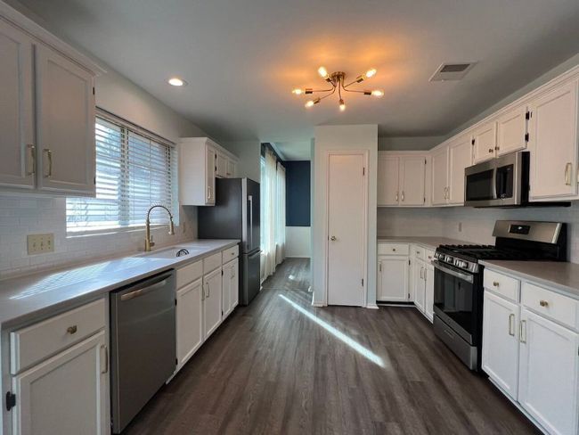 Kitchen with appliances with stainless steel finishes, tasteful backsplash, white cabinets, a chandelier, and recessed lighting | Image 12