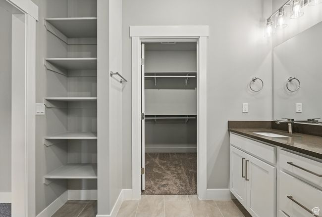 Bathroom with vanity, a walk in closet, and baseboards | Image 30