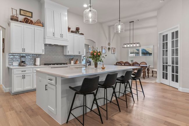 Kitchen featuring light wood-type flooring, a center island with sink, a sink, arched walkways, and custom exhaust hood | Image 5