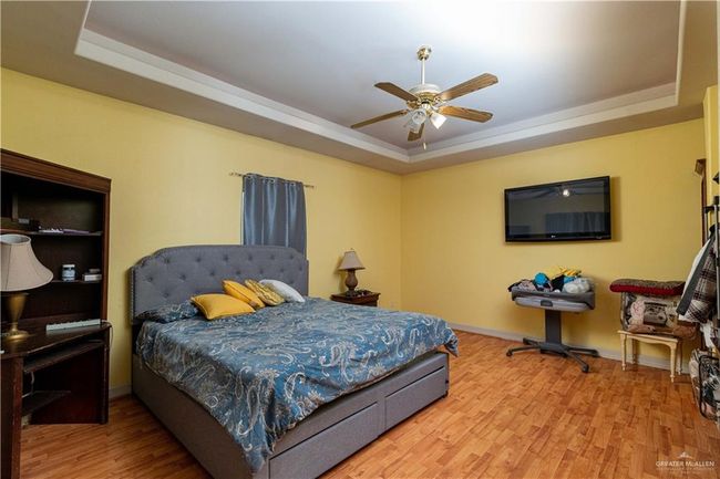 Bedroom featuring ceiling fan, a raised ceiling, and hardwood / wood-style floors | Image 22