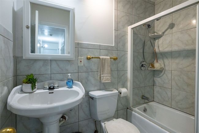Bathroom featuring shower / bathtub combination, toilet, tile walls, and a sink | Image 13