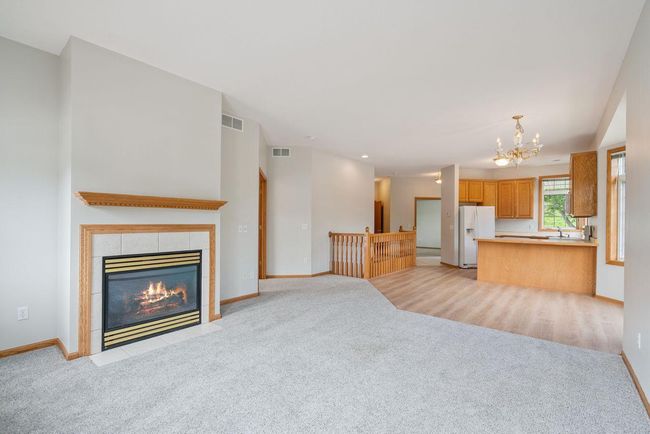 Spacious open concept living room with natural gas burning fireplace, neighboring informal dining area & kitchen. Door leading out to large back deck (28x10). | Image 7