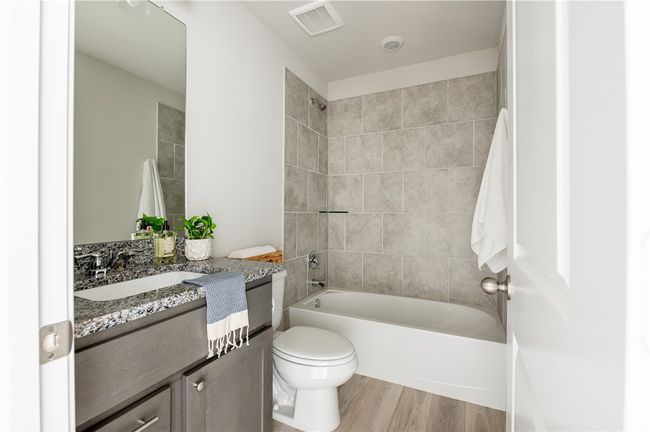 Bathroom with vanity, wood finished floors, visible vents, shower / bath combination, and toilet | Image 18