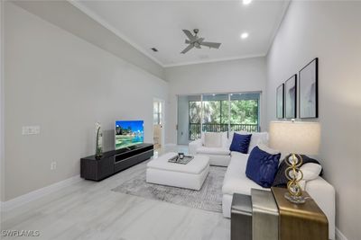 Living room featuring a towering ceiling, ceiling fan, and ornamental molding | Image 1