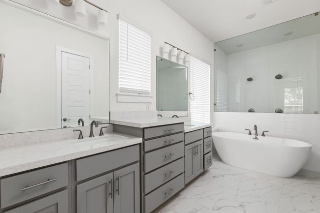 Bathroom with double vanity, a freestanding bath, marble finish floors, and tiled shower | Image 21