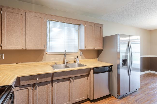 Kitchen featuring light wood-style flooring, a sink, light countertops, and appliances with stainless steel finishes | Image 16