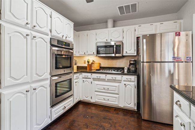 Kitchen featuring appliances with stainless steel finishes, white cabinetry, and dark wood finished floors | Image 5