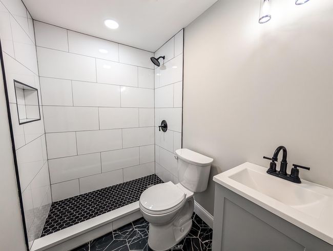 Bathroom featuring baseboards, tiled shower, vanity, and toilet | Image 22