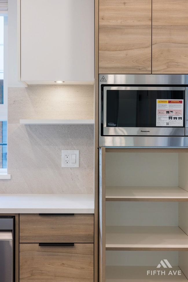 Kitchen featuring stainless steel microwave, modern cabinets, light countertops, and white cabinetry | Image 13