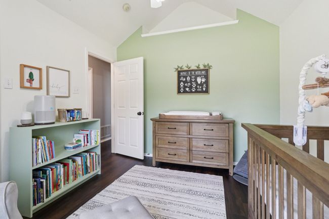 Bedroom with vaulted ceiling, dark wood finished floors, and a nursery area | Image 31