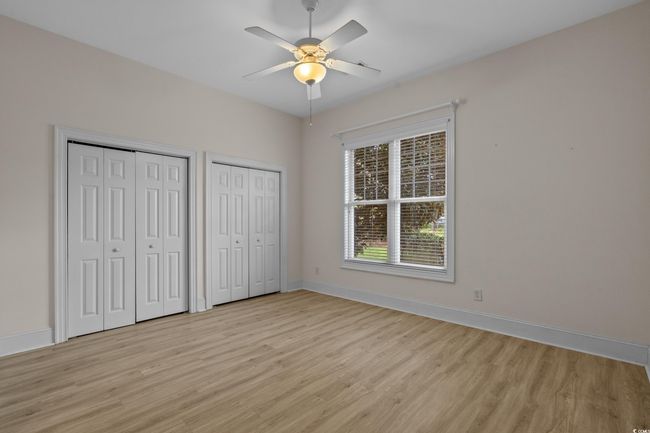 Unfurnished bedroom with light wood finished floors, multiple closets, and ceiling fan | Image 25